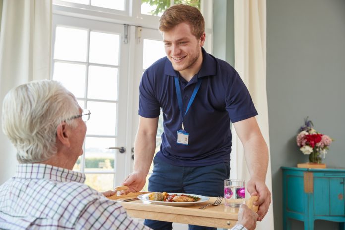 care provider serving breakfast to elderly